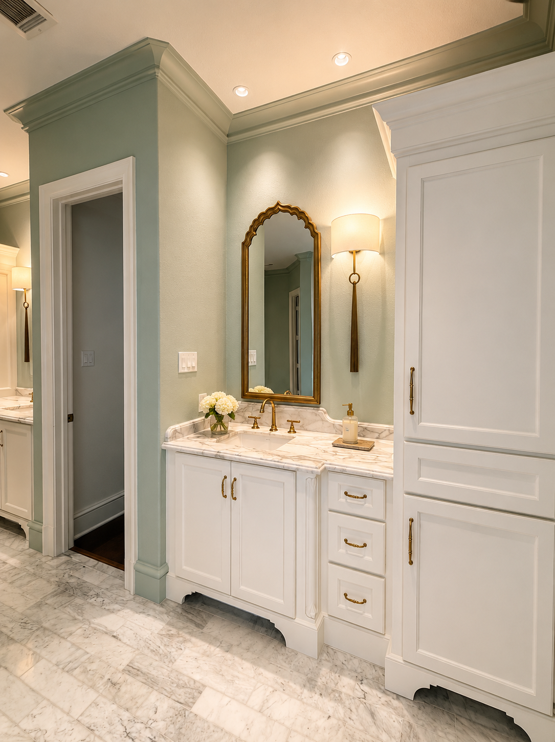 Soft sage primary bathroom vanity with marble countertop, brass fixtures, and custom millwork.